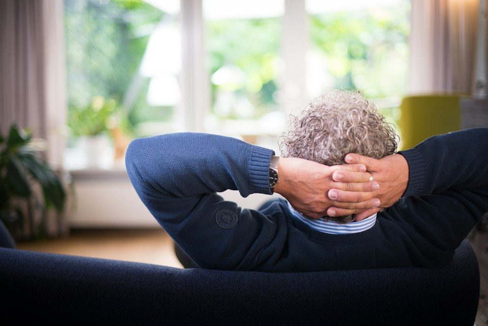 A man relaxing at home with his hands behind his head